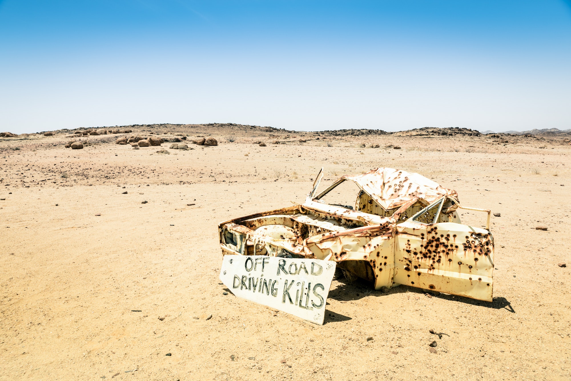 Car wreck in the namibian desert - Danger sign about driving off roads
