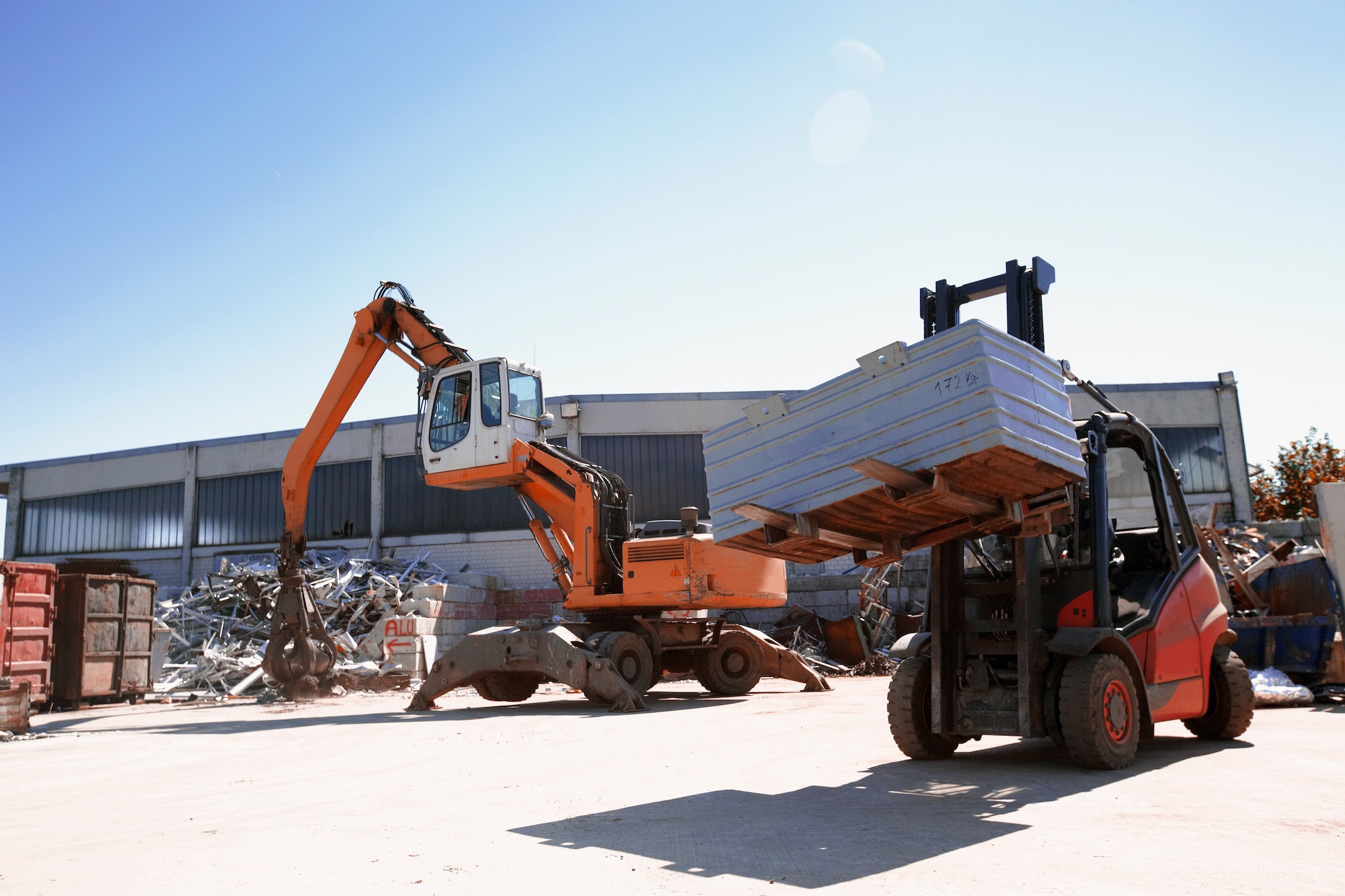 Crane grab and fork lift truck sorting and moving metals in scrap yard