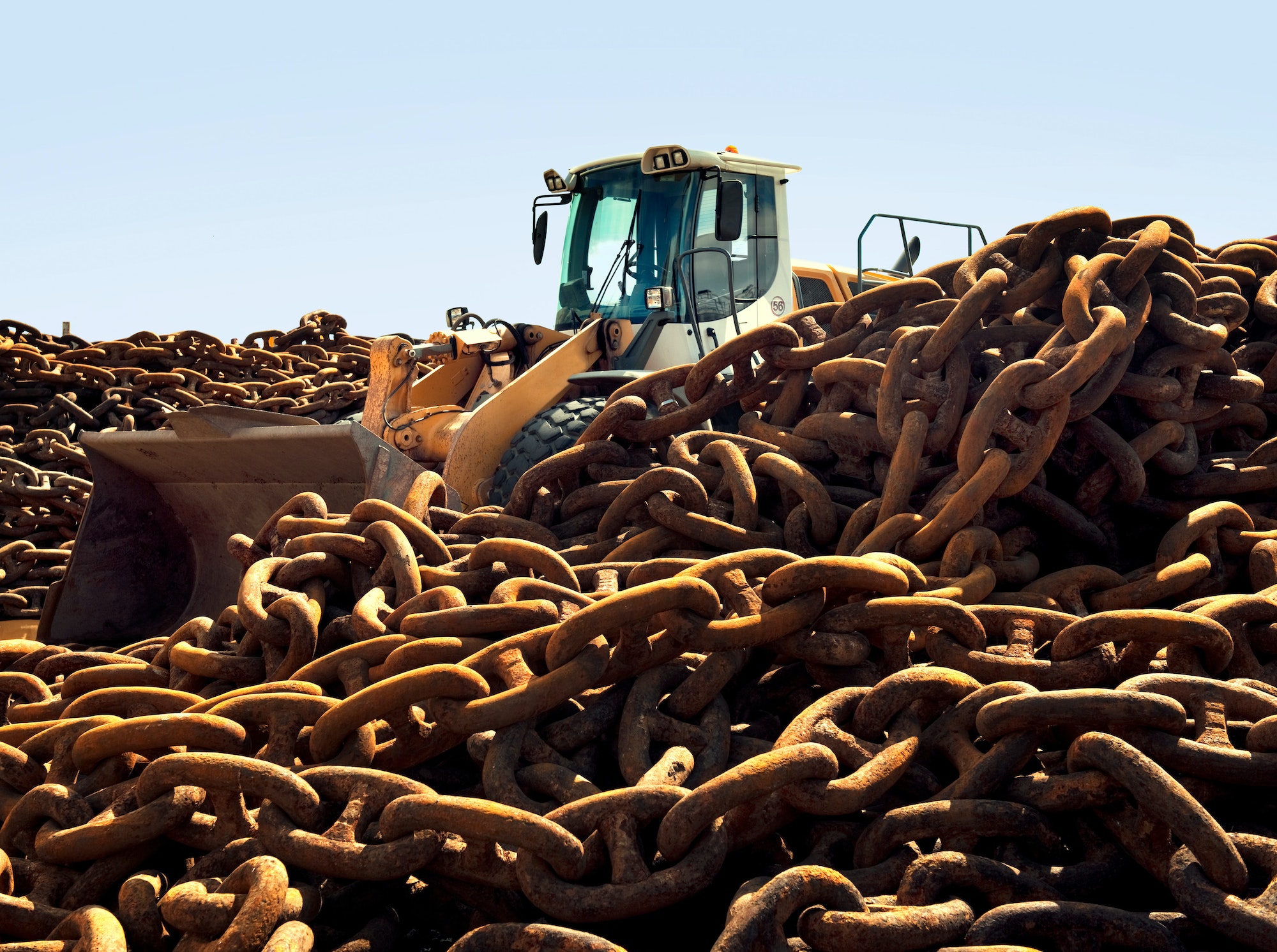 Rusted chains and excavator in scrap yard